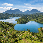 Children overlooking terraced green hills surrounding a blue lake with volcanoes behind